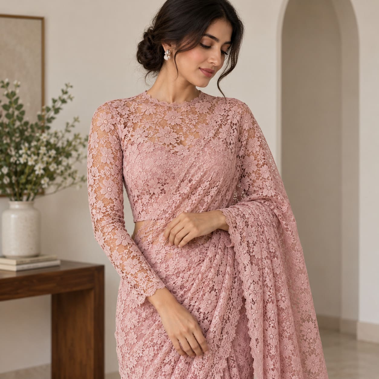 Woman wearing a full pink floral lace saree with matching lace blouse and drape